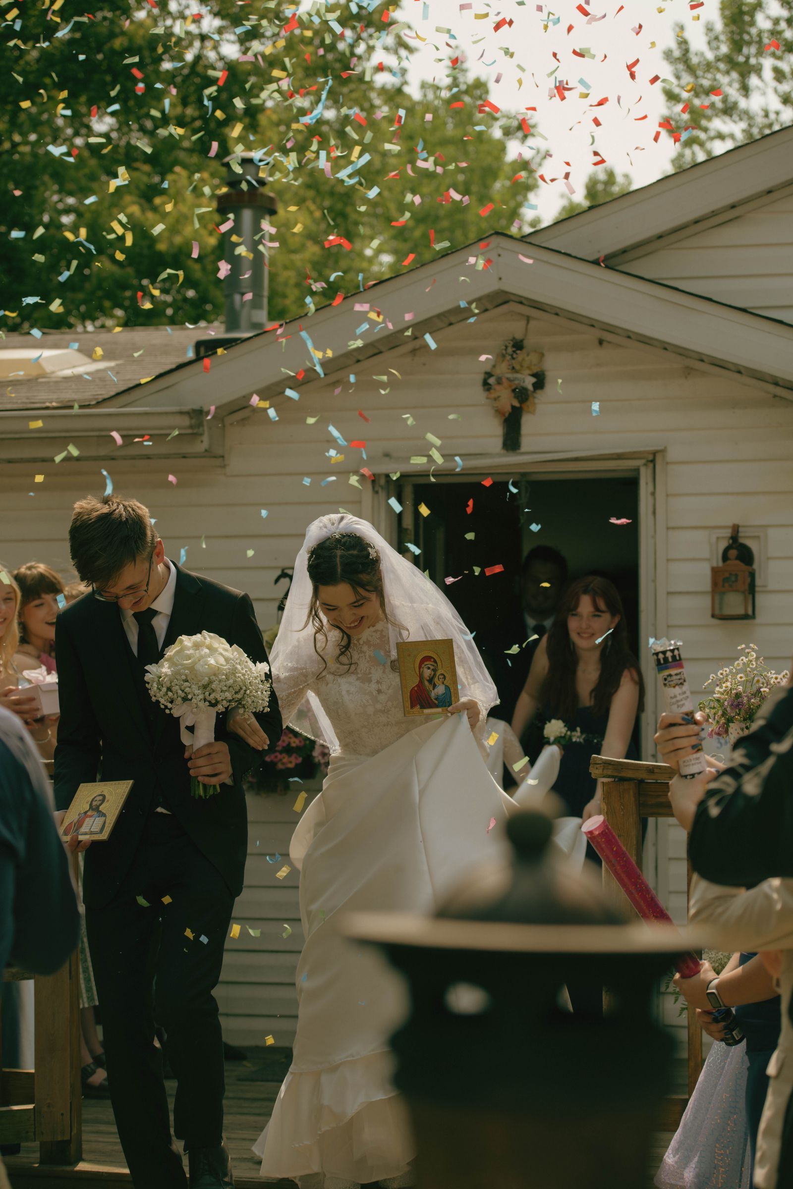A bride and groom leaving their ceremony under a shower of colourful confetti