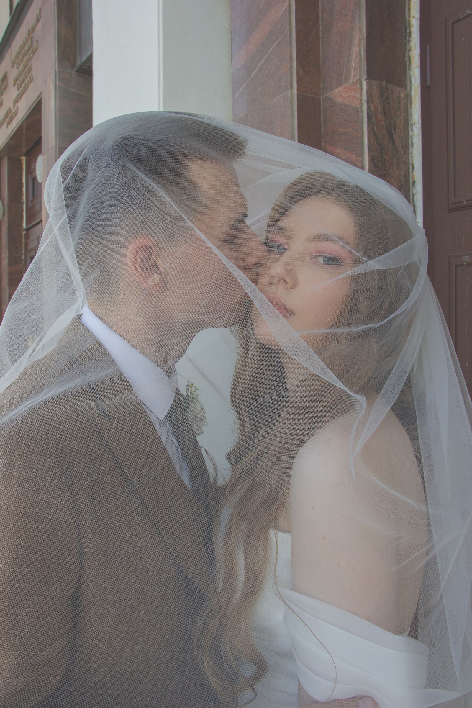 A bride and groom sharing a kiss beneath her veil