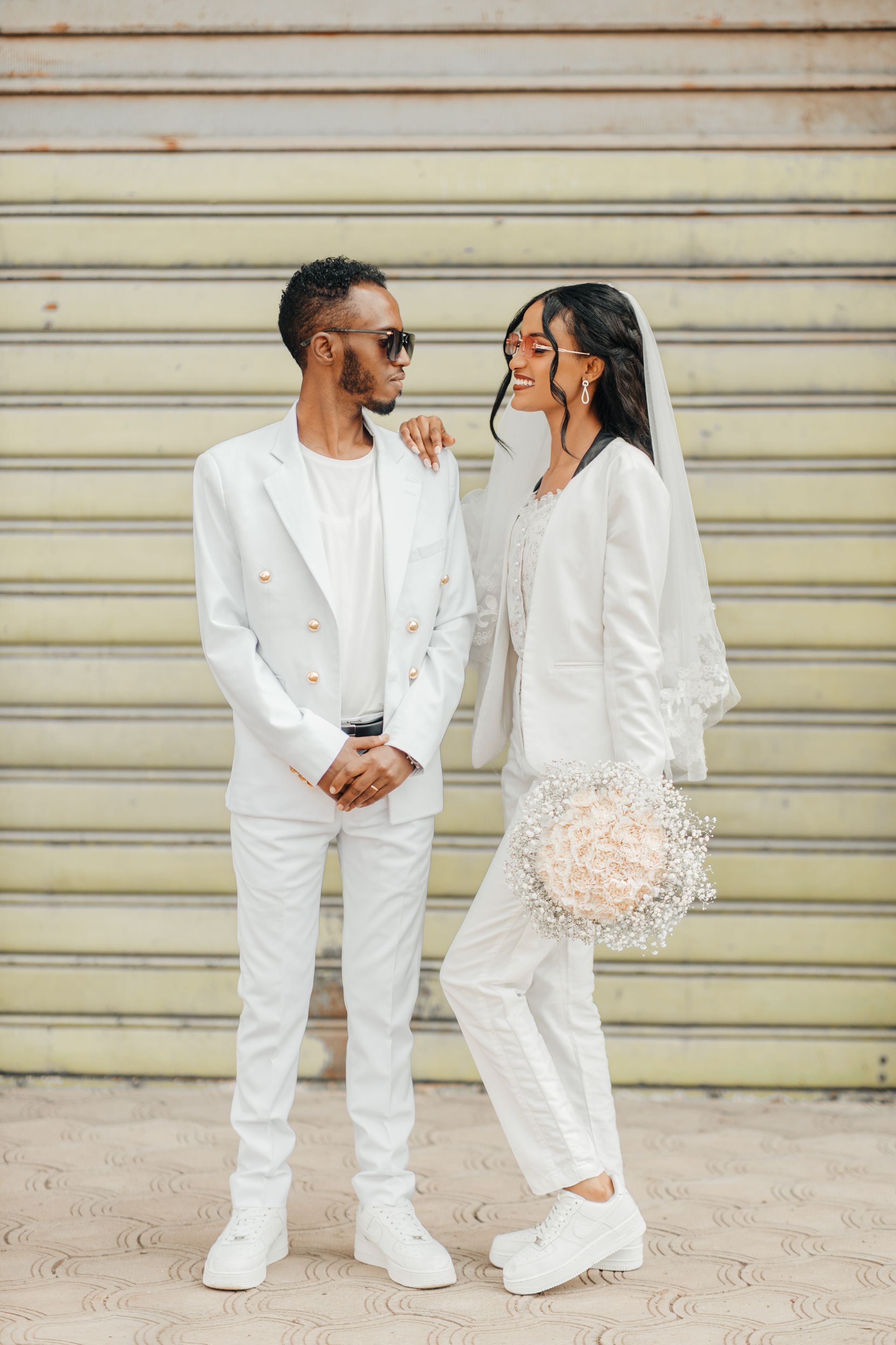 A stylish couple in matching white suits on their wedding day